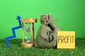 Sticky note with word Profit, money of bag, up arrow and sandglass against green background