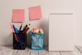 Neat Workplace with 2 Empty Colored Stick Pad Notes Put on White Wall Hanging above 2 Mesh Pencil Pots and Open Spiral