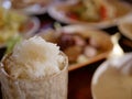 Sticky rice in small serving bamboo basket on a defocused background of variety of Thai foods Royalty Free Stock Photo