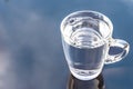 Still clean drinking water in transparent glass on surface reflected against blue sky and cloud Royalty Free Stock Photo