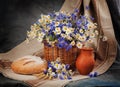 Still Daisies and cornflowers in the basket. Bread and milk on t