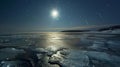 A still lake its icy surface illuminated by the shimmering light of the full moon as the vibrant streaks of the Northern