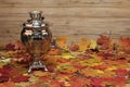 Still life art photography with an antique samovar with autumn leaves on a wooden background