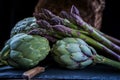 A still life of artichokes with knife and asparagus on the rustic textured background close side view low key Royalty Free Stock Photo