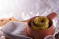 A baked apple in a clay pot on a linen cloth and wooden desk against white background Royalty Free Stock Photo