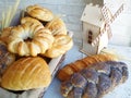 Still-life with baked goods in basket, spikelets of wheat and decorative wood wind mill