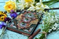 Still life with beautiful flowers and magic book of spells or diary. Occult, esoteric and witchcraft concept. Mystic wicca Royalty Free Stock Photo