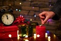 Black alarm clock with midnight on dial and woman's hand lights candle with matches. Merry Christmas