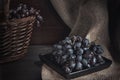 Still life with black grapes and basket on burlap, rustic style, low key Royalty Free Stock Photo