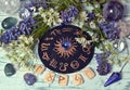 Still life with black zodiac circle, runes, crystal and flowers on witch altar table