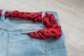 Still life of blue jeans with a brown leather belt on a light wood background