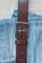 Still life of blue jeans with a brown leather belt on a light wood background Royalty Free Stock Photo