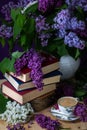 Still life books, coffee and lilacs in the dark key.Spring background