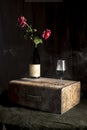 still life bottle and glass of wine with red roses, high contrast, black background