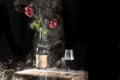 still life bottle and glass of wine filled with white smoke with red roses, high contrast, black background