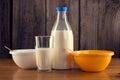 Still life of bottle of milk with glass and two plastic bowls over wooden background