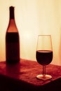 still life of bottle of red wine and a glass with warm sunset background