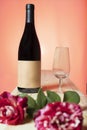 still life of bottle of red wine and a glass with roses with warm sunset background