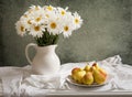 Still life with bouquet of daisy flowers in a jar and fresh pear Royalty Free Stock Photo