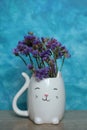 A bouquet of dried flowers in a white cat vase on a blue background Royalty Free Stock Photo