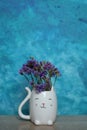 A bouquet of dried flowers in a white cat vase on a blue background Royalty Free Stock Photo