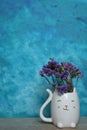 A bouquet of dried flowers in a white cat vase on a blue background Royalty Free Stock Photo