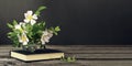 Still life with bouquet of flowers in vase and old book on dark background Royalty Free Stock Photo