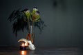 Still life with a bouquet of protea, black burning candle and a goat skull on a dark background, selective focus