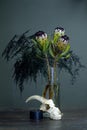 Still life with a bouquet of protea, black candle and a goat skull on a dark background, selective focus