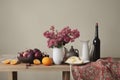 still life with a bouquet of red and white flowers and a vase of fruits on a wooden table in a roomstill life with a bouquet of re Royalty Free Stock Photo