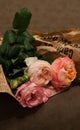 Three delicate rose flowers wrapped in the newspaper