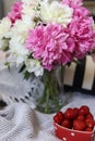 a still life with a bouquet of white and pink peonies and strawberries Royalty Free Stock Photo