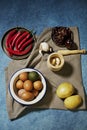 Still life with a bowl of raw eggs, raw potatoes, garlic in a wooden mortar, dried peppers and red hot peppers