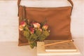 Still life brown leather bag,book memo and rose bouquet on white wooden board