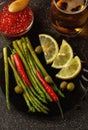 Still-life. A bunch of asparagus on a dark plate, a Cup of red caviar and a glass of light beer Royalty Free Stock Photo