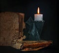 still life with a burning candle and a candlestick in the form of a monk and old books.