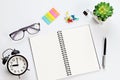 Working desk with open notebook, eyeglasses and alarm clock