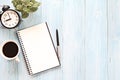 Open notebook with blank pages, coffee cup and clock on wooden desk table Royalty Free Stock Photo