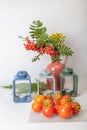 Still life, Candlesticks, vase with yellow flowers and rowan, fresh tomatoes.Concept, autumn harvest, vegetables without