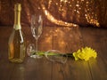 Still life with champagne and two glasses and a bunch of daffodils on a wooden table, Glittery bokeh background Royalty Free Stock Photo