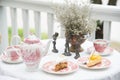 Still life with china cup of tea, fruit cake,vintage milk jug, vintage flora on aged white table at balcony for breakfast Royalty Free Stock Photo