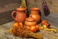 Still life with clay jugs of various sizes and bundles of dried medicinal herbs on wooden table