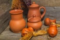 Still life with clay jugs of various sizes and bundles of dried medicinal herbs on wooden table