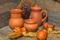 Still life with clay jugs of various sizes and bundles of dried medicinal herbs on wooden table