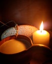 Still life: a clay mug with milk, a piece of bread and ears of wheat with a burning candle Royalty Free Stock Photo