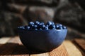 Still life. Close-up. Blue bowl of fresh wild blueberries from an organic farm on rustic wood crate and stone background Royalty Free Stock Photo