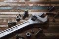 Still life close up of forged Steel adjustable wrench, nuts and bolts on wood plank background Royalty Free Stock Photo