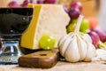 Still life - close up view of yellow and red muscat grape, cheese, garlic and a glass of wine on a wooden board and canvas Royalty Free Stock Photo