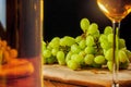 Still life of cluster of white grapes on a wooden board. Glass and bottle of white wine. Black background. Wine making concept. Royalty Free Stock Photo