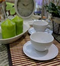 Still life - coffee mugs arranged on a table with vintage clocks and decorative green candles Royalty Free Stock Photo